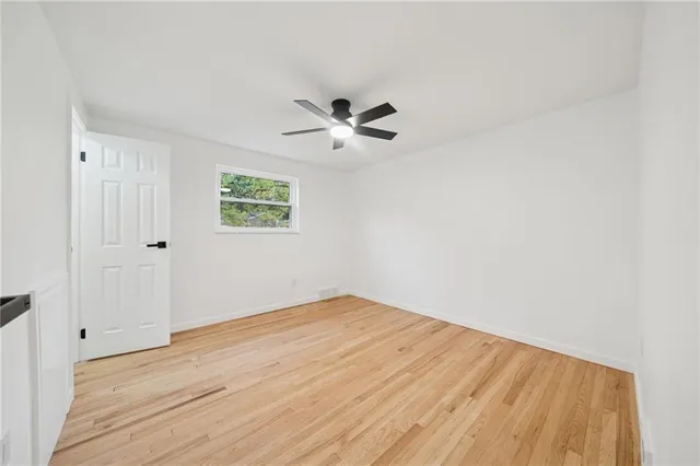 an empty room with wooden floor and ceiling fan