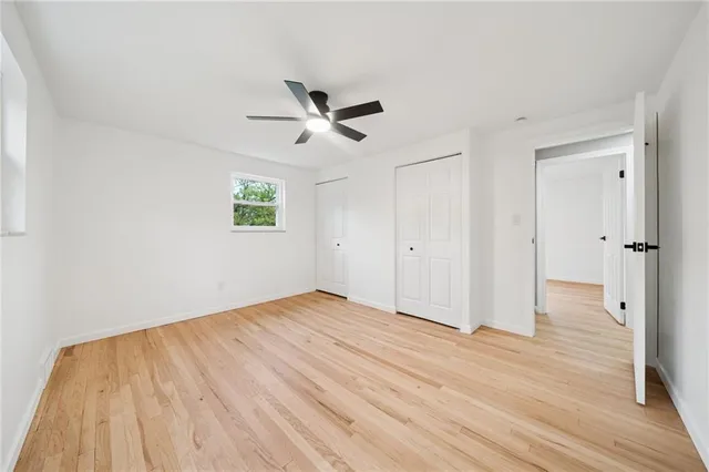 a view of empty room with wooden floor and ceiling fan