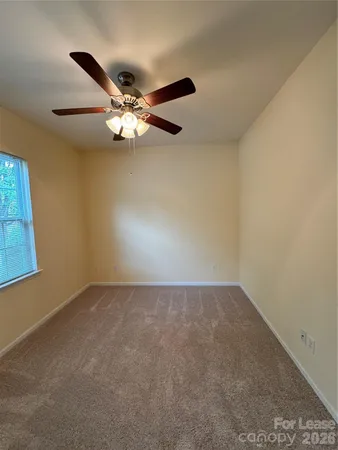 an empty room with a window and a fan