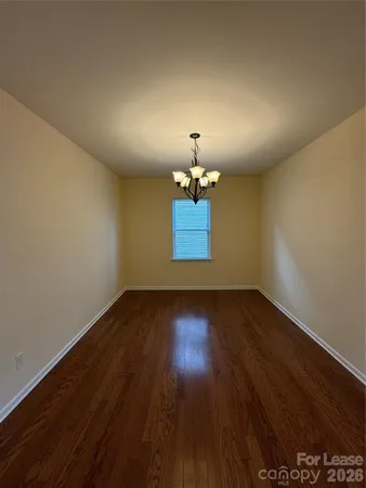 an empty room with wooden floor chandelier fan and windows