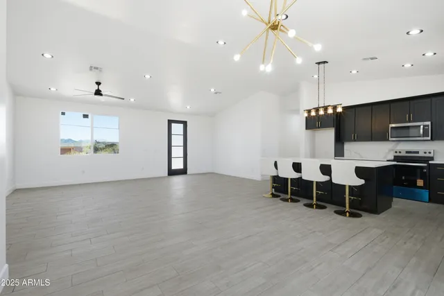 a view of an empty room with kitchen and window