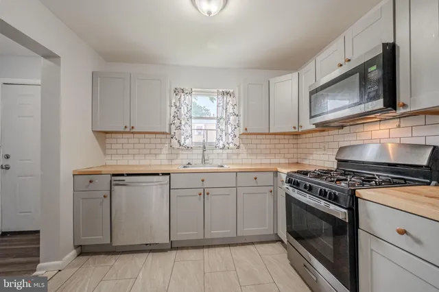 a kitchen with granite countertop white cabinets stainless steel appliances and a sink