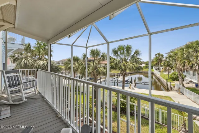 a view of a white house with a yard and palm trees