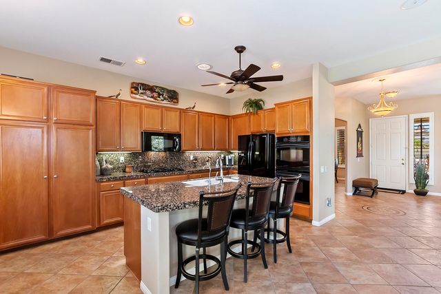 a kitchen with stainless steel appliances kitchen island granite countertop a table chairs sink and cabinets