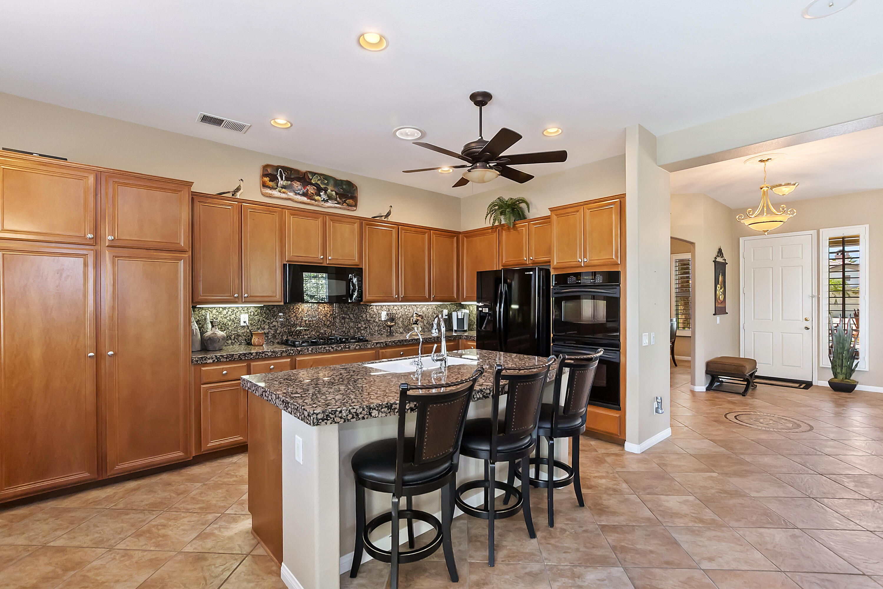 43328 Bordeaux Drive La Quinta, CA 92253 - Photo 11 of 38 a kitchen with stainless steel appliances kitchen island granite countertop a table chairs sink and cabinets