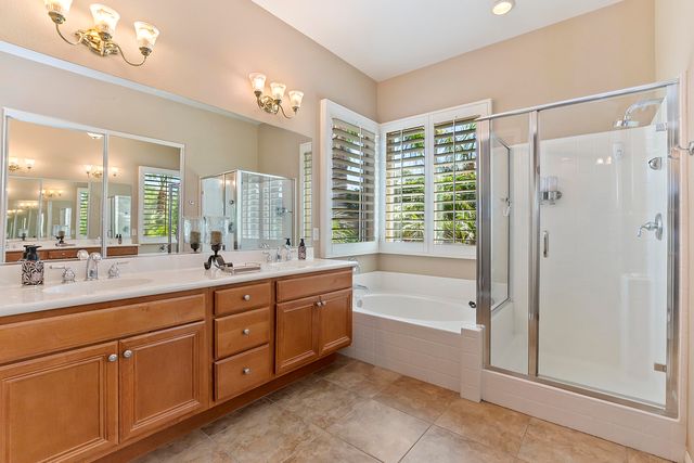 a spacious bathroom with a double vanity sink a large mirror and a bathtub with shower