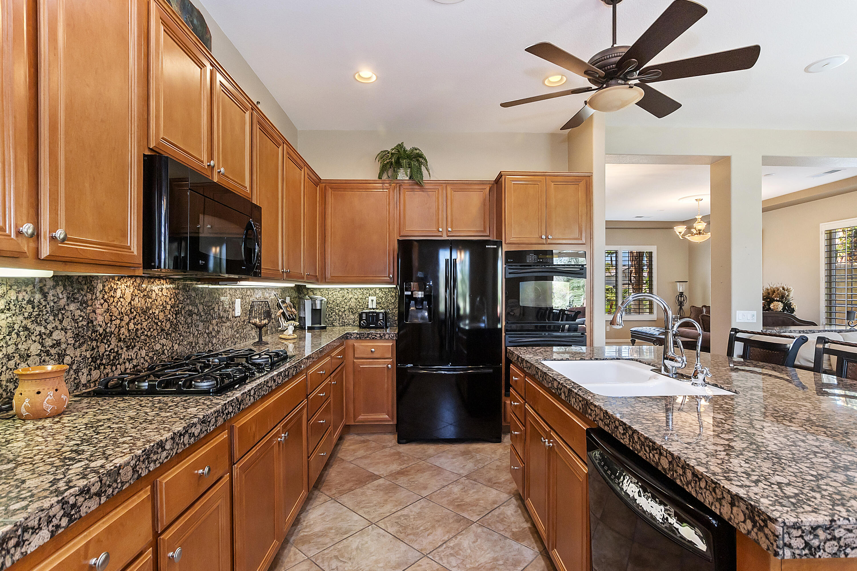43328 Bordeaux Drive La Quinta, CA 92253 - Photo 10 of 38 a kitchen with stainless steel appliances granite countertop a sink a stove and a wooden cabinets