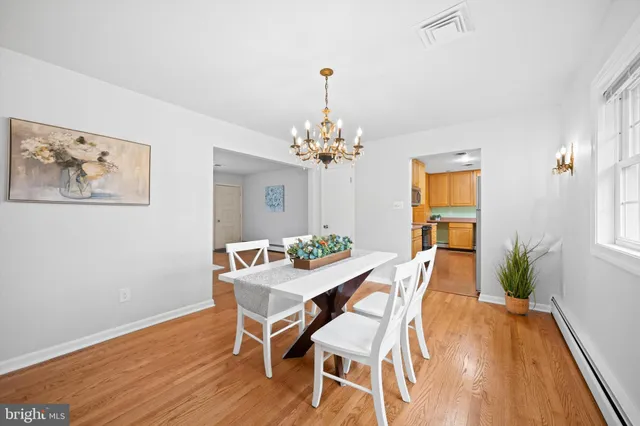 a dining room with chandelier and wooden floor