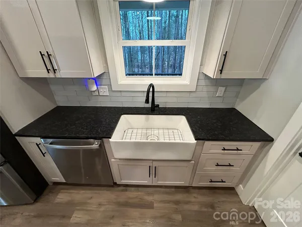 a kitchen with stainless steel appliances granite countertop white cabinets and window