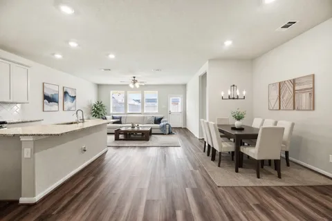 a living room with stainless steel appliances granite countertop furniture wooden floor and a view of kitchen