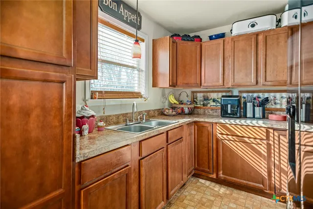 a kitchen with stainless steel appliances granite countertop a sink window and cabinets