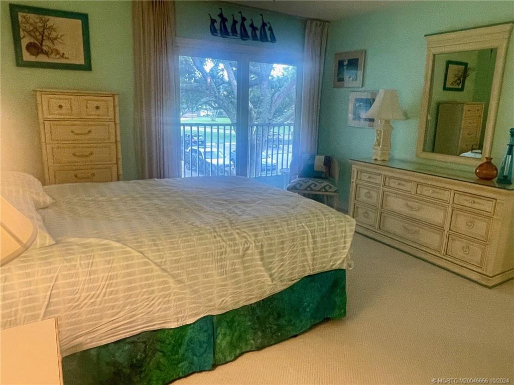 1225 Northwest 21st Street, Unit 3014 Stuart, FL 34994 - Photo 19 of 37 a bedroom with a bed a mirror on dresser and a large window