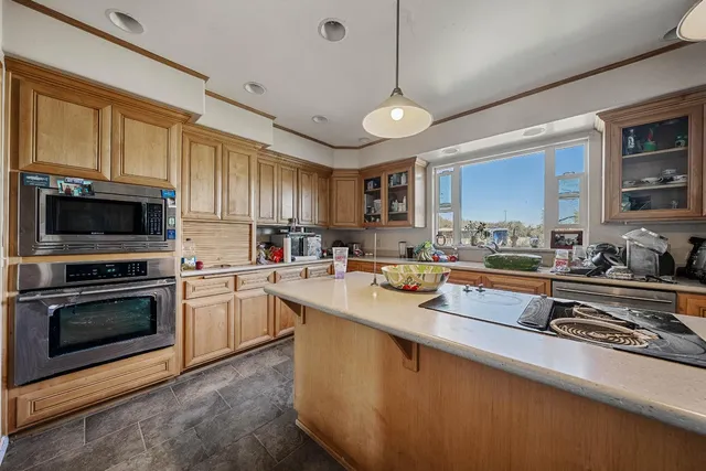 a kitchen with stainless steel appliances granite countertop a stove top oven a sink a refrigerator and white cabinets
