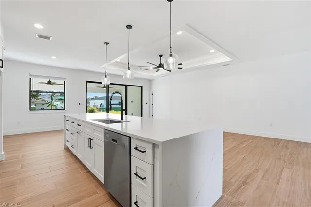 a large kitchen with a large window a island a stove and wooden floor
