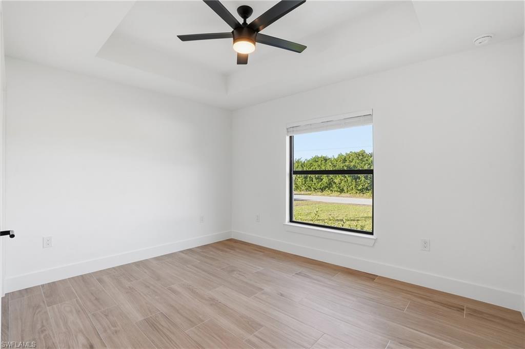 3903 15th Street Southwest Lehigh Acres, FL 33976 - Photo 23 of 44 an empty room with wooden floor a ceiling fan and windows