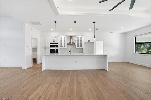 a large kitchen with stainless steel appliances a large counter top a wooden floor and a large window