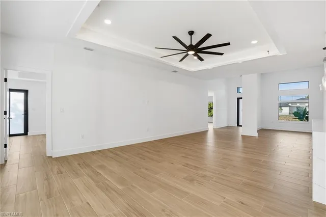 a view of an empty room with wooden floor and a ceiling fan