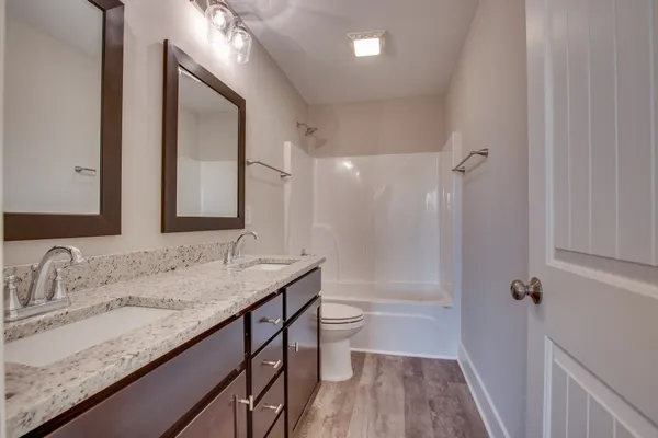 a bathroom with a granite countertop sink a toilet and a mirror