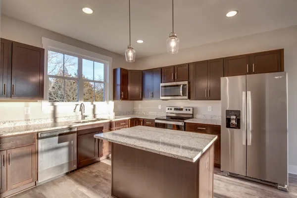 a kitchen with stainless steel appliances granite countertop a refrigerator a sink a stove and oven