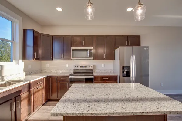 a kitchen with stainless steel appliances kitchen island granite countertop a sink and a stove