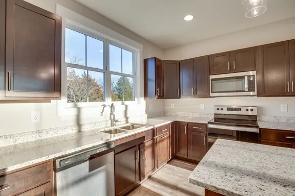 a kitchen with stainless steel appliances wooden cabinets a stove a sink and a microwave