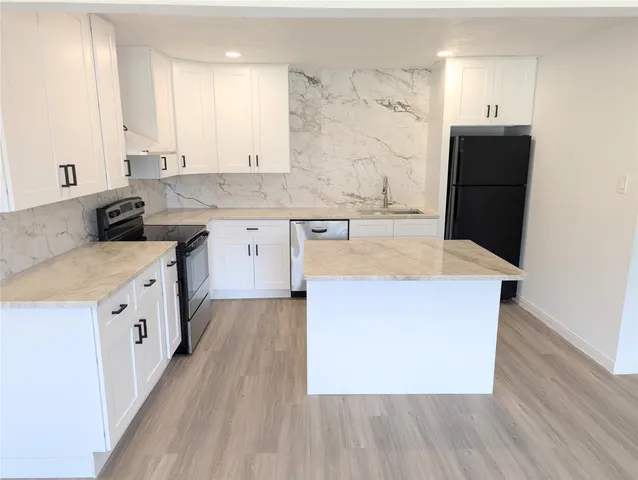 a large kitchen with stainless steel appliances granite countertop a stove a sink dishwasher and a refrigerator with wooden floor