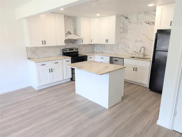 a kitchen with a sink a stove a refrigerator and white cabinets
