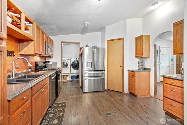 a kitchen with a sink wooden floor and stainless steel appliances