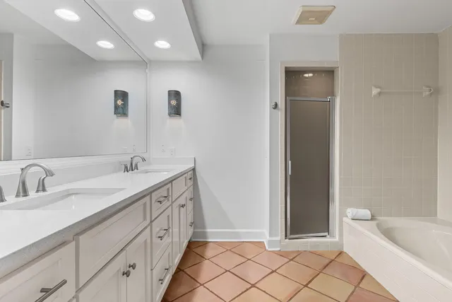 a spacious bathroom with a double vanity sink mirror and bathtub