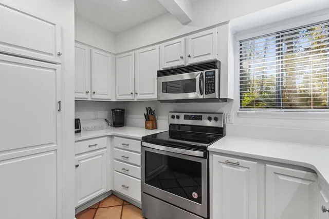 a kitchen with white cabinets stainless steel appliances and a window