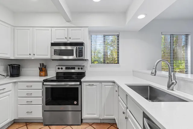 a kitchen with granite countertop a sink stainless steel appliances and cabinets