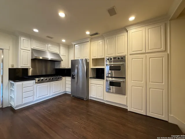 a kitchen with stainless steel appliances white cabinets and wooden floors