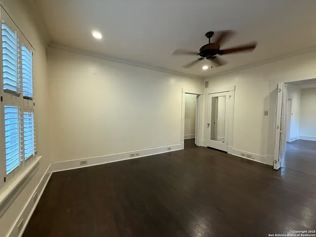 an empty room with wooden floor fan and windows