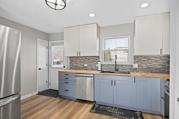 a kitchen with stainless steel appliances granite countertop a sink a stove a refrigerator and island with wooden floor