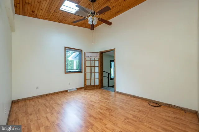 a view of an empty room with wooden floor and a ceiling fan