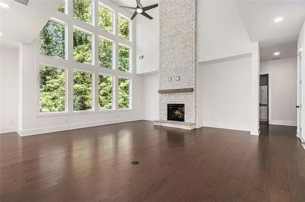 an empty room with wooden floor fire place and windows