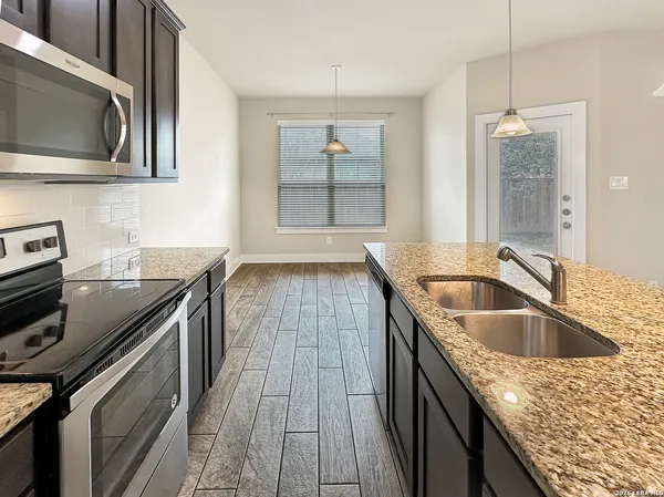 a kitchen with granite countertop a sink stove and cabinets