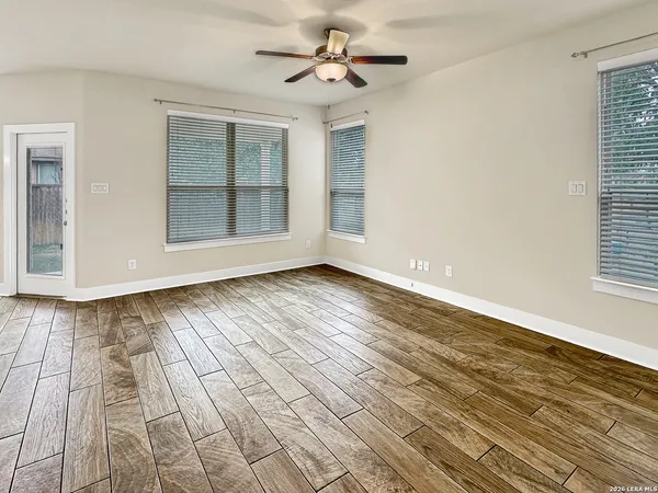 a view of an empty room with wooden floor and a window