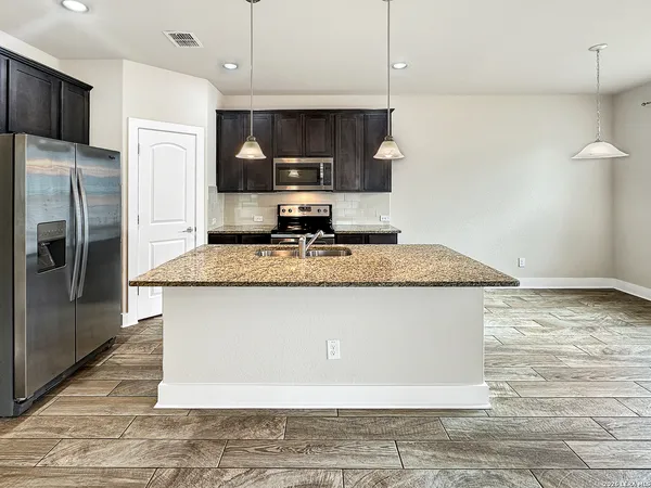 a view of a kitchen with granite countertop stainless steel appliances and a refrigerator