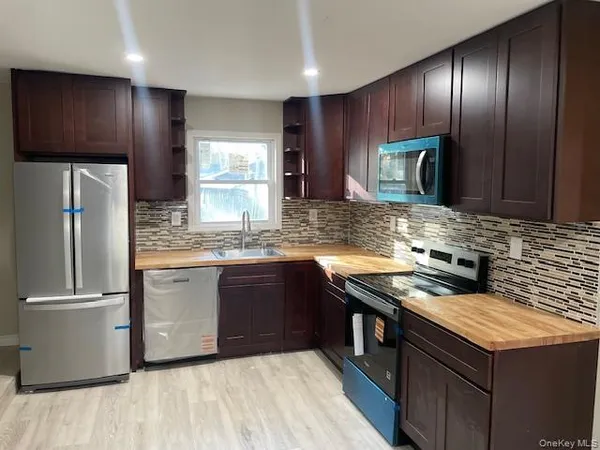 a kitchen with stainless steel appliances granite countertop wooden cabinets a stove a sink and a refrigerator