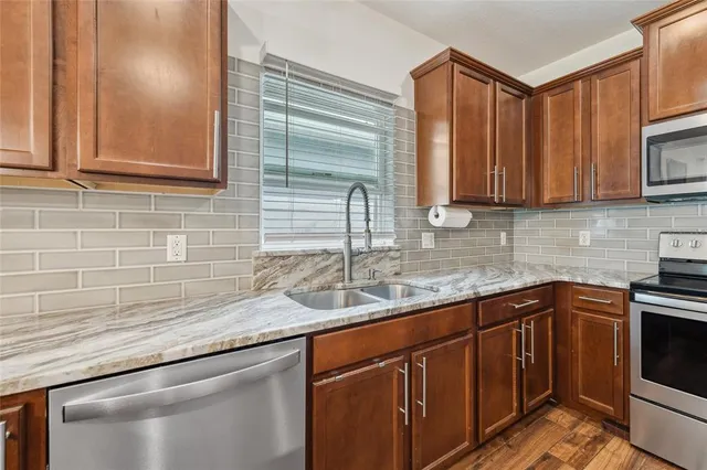 a kitchen with stainless steel appliances granite countertop a sink a stove and cabinets