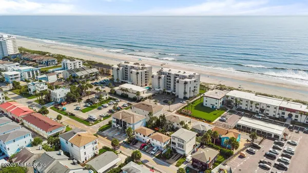 an aerial view of residential houses with outdoor space and ocean view