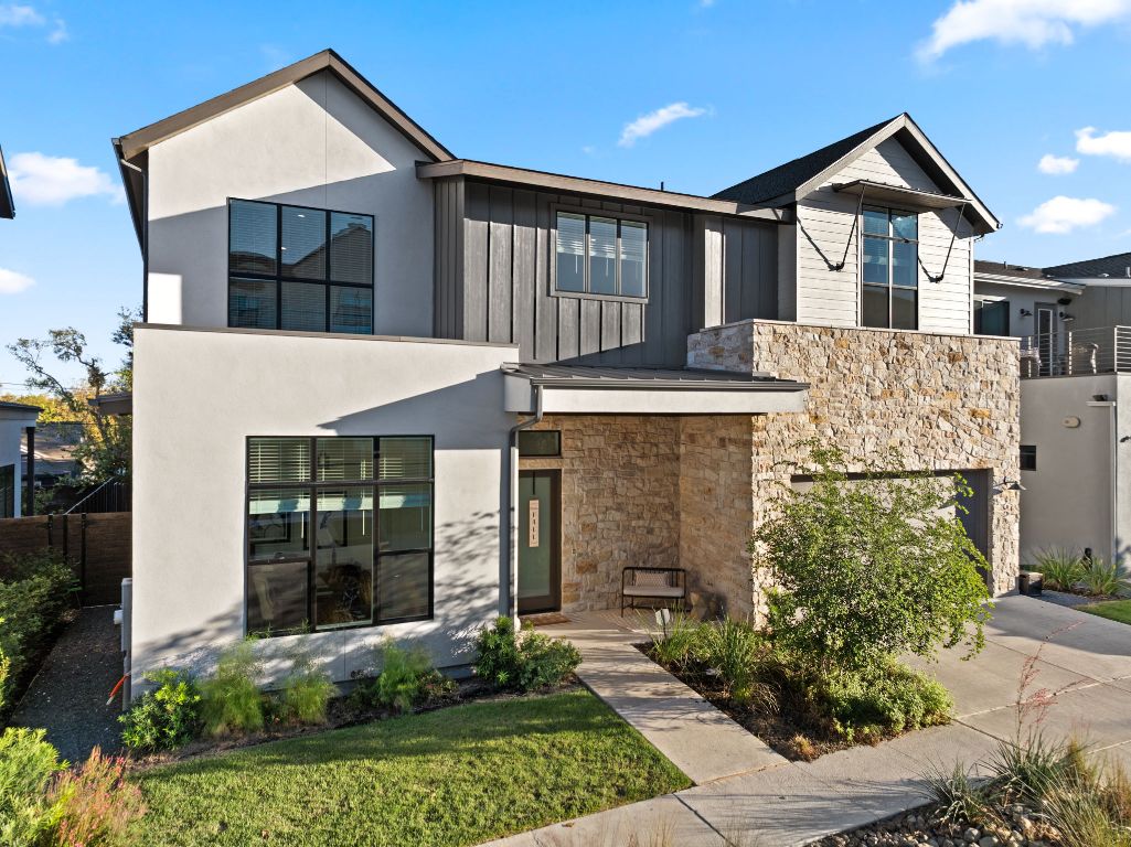 Modern home featuring stone siding, a garage, board and batten siding, and concrete driveway