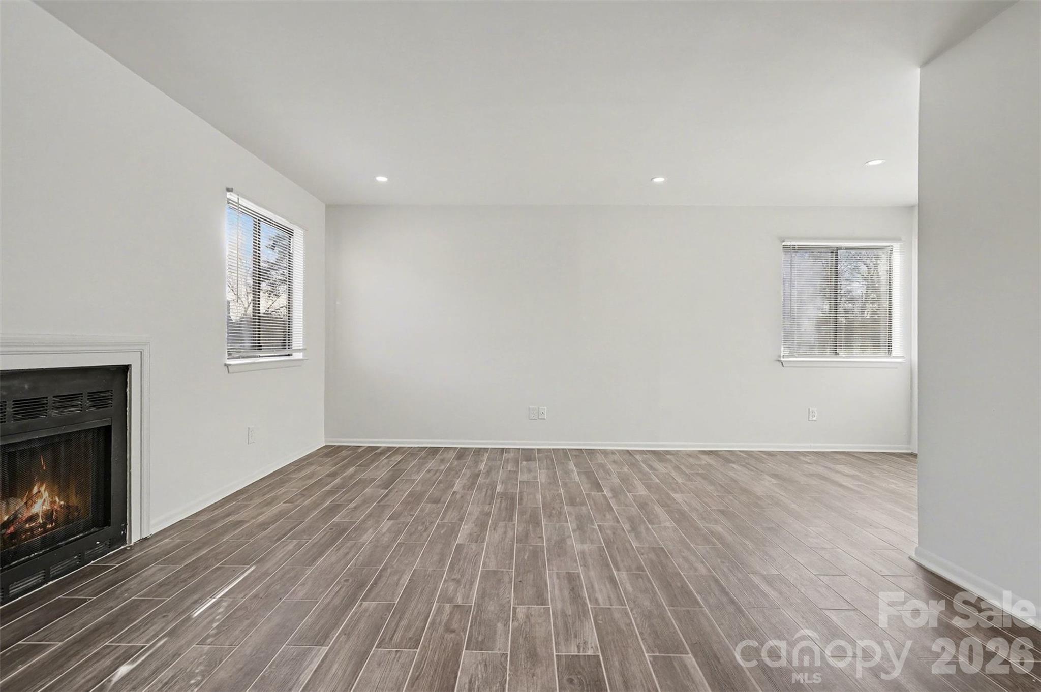 6148 Heath Ridge Court Charlotte, NC 28210 - Photo 8 of 27 an empty room with wooden floor a fireplace and windows