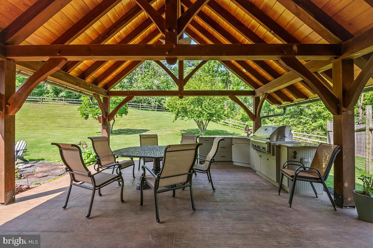 1621 Limekiln Road Oley, PA 19547 - Photo 19 of 75 a view of a patio with table and chairs and couches with wooden roof and stairs