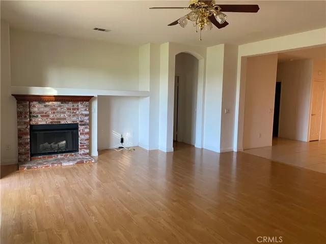 a view of an empty room with a fireplace and a chandelier fan