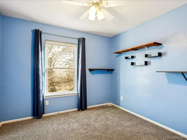 an empty room with a window and a chandelier fan