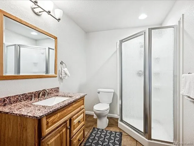 a bathroom with a granite countertop sink toilet and shower