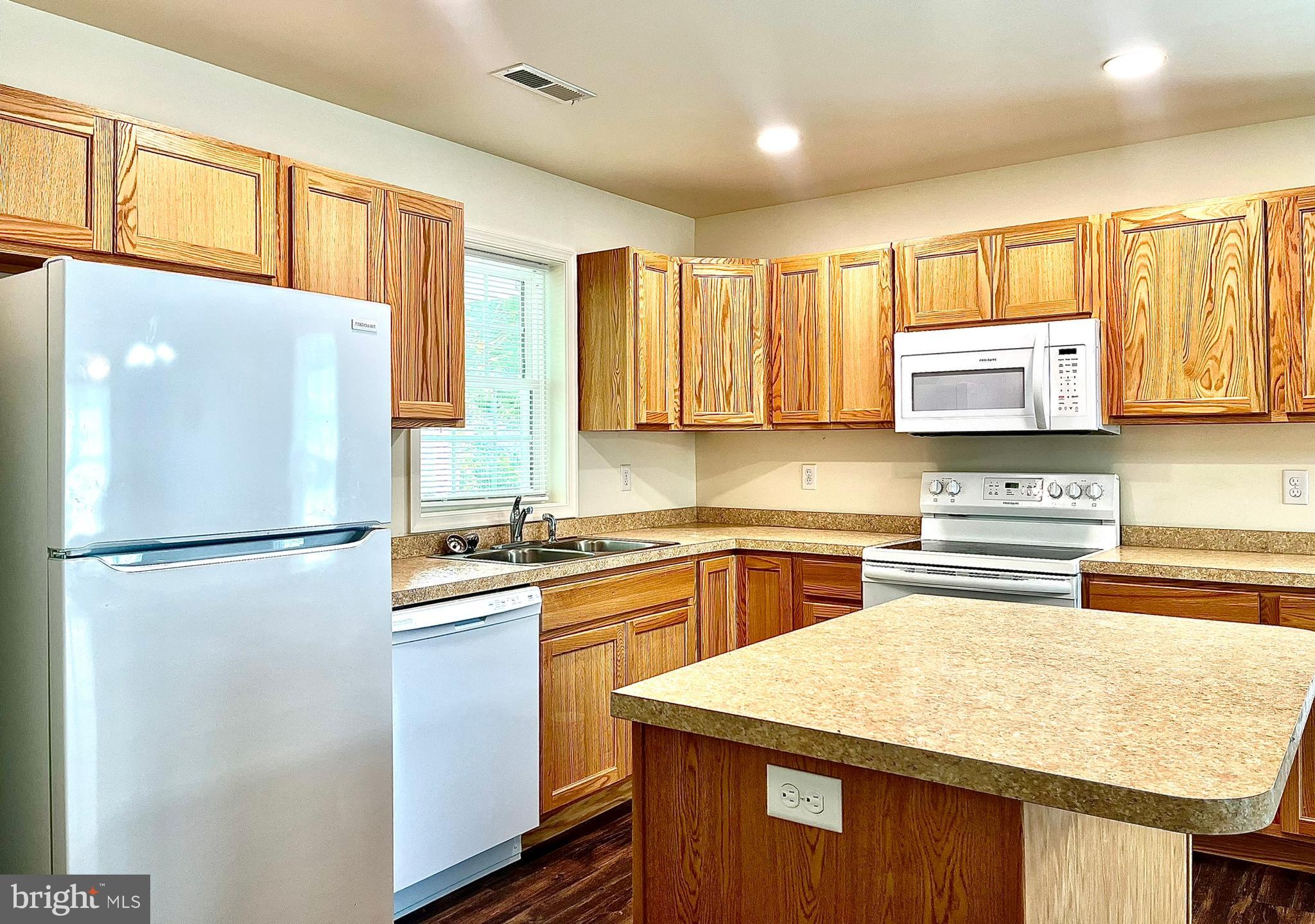 46 Meadowood Lane Harrington, DE 19952 - Photo 4 of 15 a kitchen with stainless steel appliances granite countertop a refrigerator a sink dishwasher a stove with wooden cabinets and floor