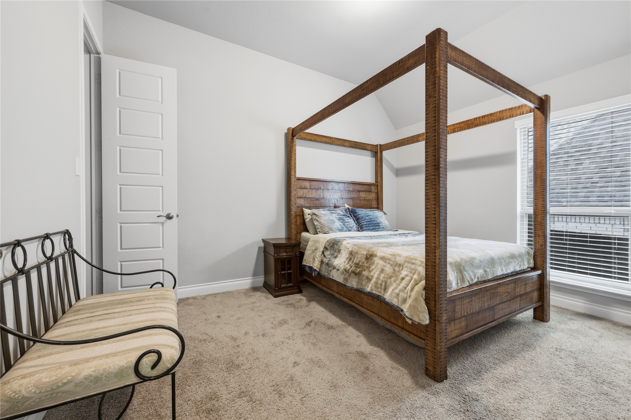 140 Catani Loop Georgetown, TX 78628 - Photo 5 of 36 A spacious bedroom features a robust wooden four-poster bed and soft carpeting, illuminated by natural light from a large window.